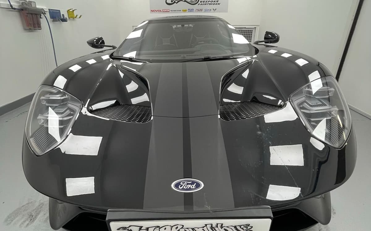 Dark Ford GT with silver stripes photographed head-on in the Willoughbys spray booth