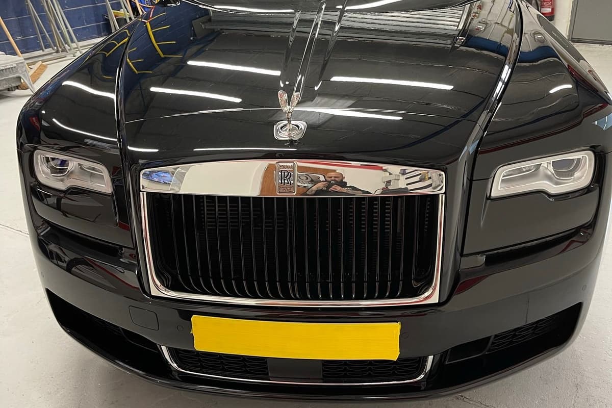 Chrome grille and Spirit of Ecstasy against the fresh black paint of a Rolls-Royce