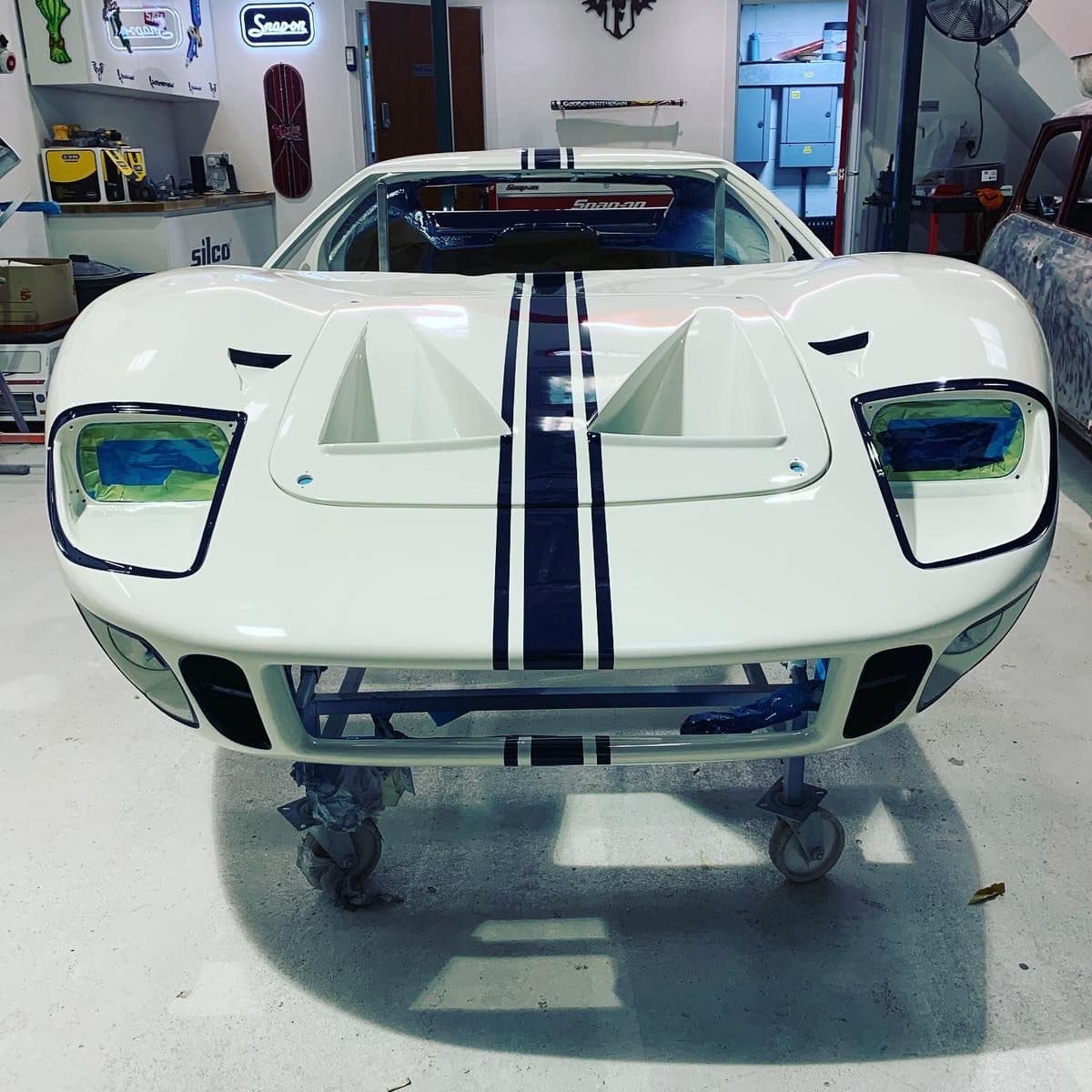 White Ford GT40 mid-build in the workshop, headlights masked off ready for paint